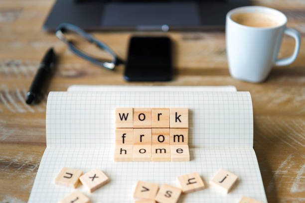 istock Closeup on notebook over wood table background, focus on wooden blocks with letters making Work From Home words 959533362