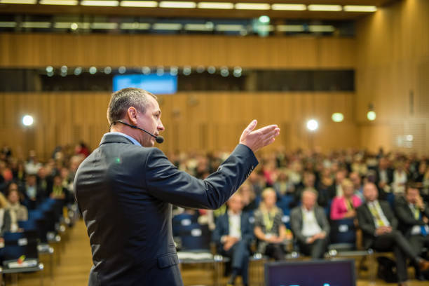 Dynamic microphone on stage in front of a large crowd in a theater.