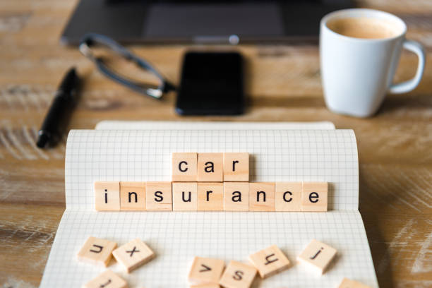 istock Closeup on notebook over wood table background, focus on wooden blocks with letters making Car Insurance words 959536192