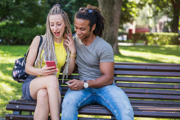 istock Young cheerful couple browsing on the phone in the park 959537884