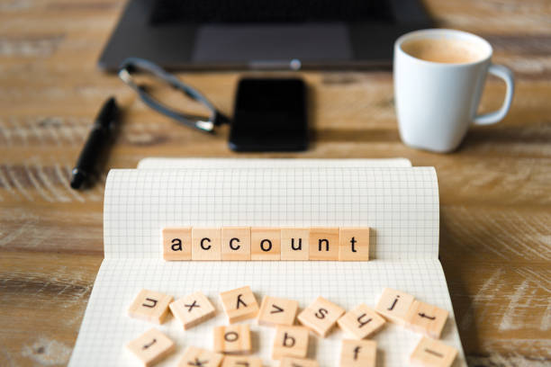 istock Closeup on notebook over wood table background, focus on wooden blocks with letters making Account word 959541032