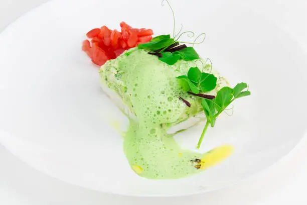 fish fillet with green herbs sauce, fresh peas and tomato salad
