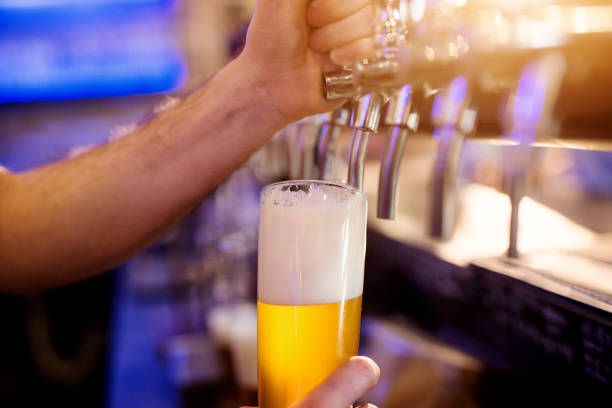 istock Close up focus view of waiter hands pouring draft beer. 959543350