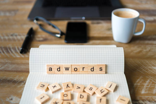 Closeup on notebook over wood table background, focus on wooden blocks with letters making Adwords word