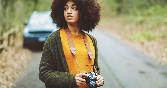 Young woman with afro hairstyle taking photos in the woods