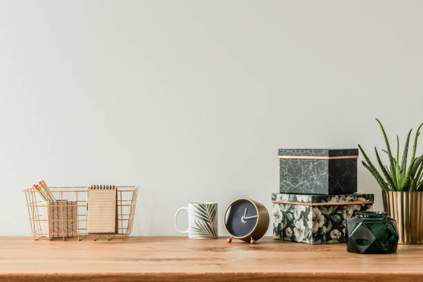 Organized table top Organized table top with floral boxes, mug, clock and metal box on empty wall copper wall stock pictures, royalty-free photos & images