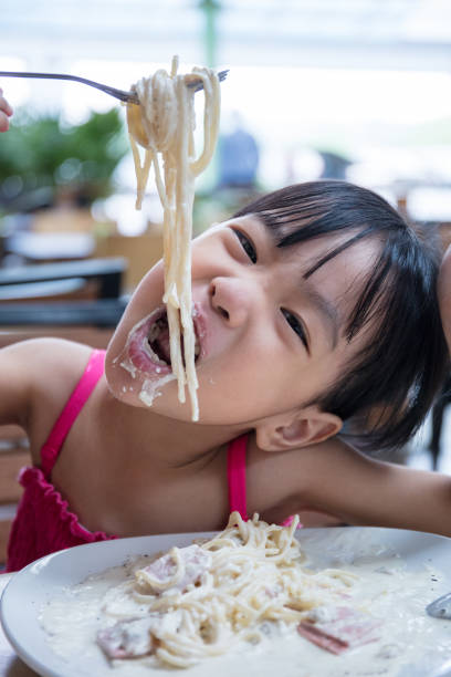 istock Asian Chinese little girl eating spaghetti 959564986