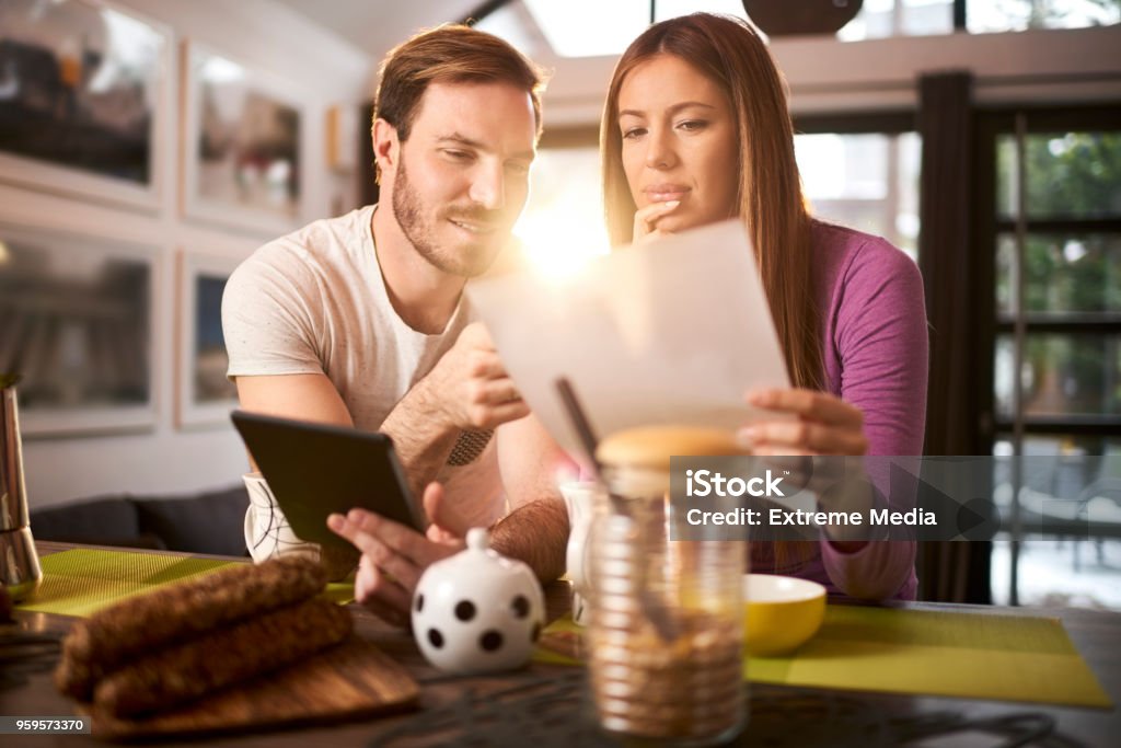 Couple at home Heterosexual couple in their house having breakfast and looking at paper document. Adult Stock Photo