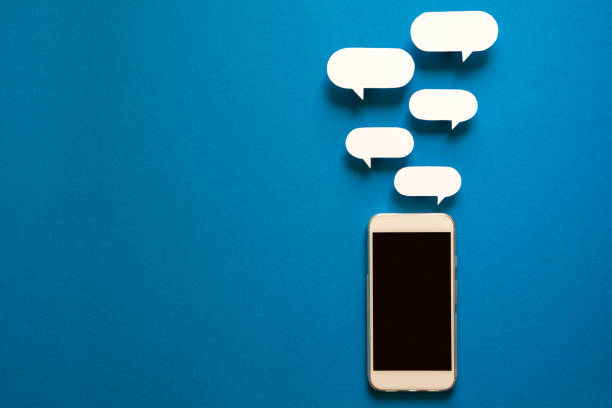 Smartphones with paper speech bubbles on blue background. Communication concept. Top view. Copy space. Paper composition