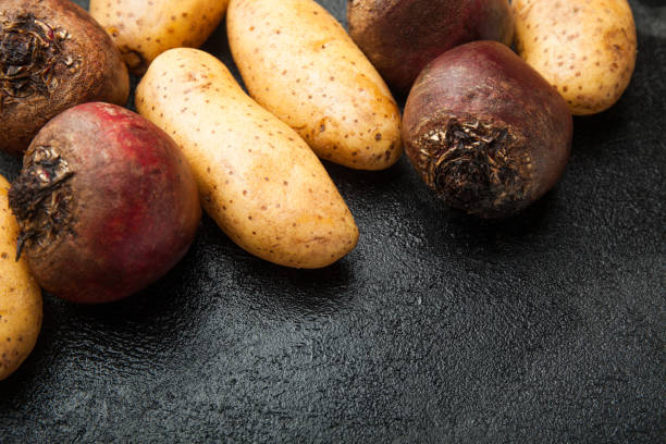 istock Potato tubers, beets and carrots on a black table 959575908