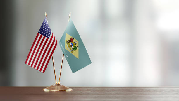 American And Delaware State Flag Pair On A Desk Over Defocused Background American and Delaware State flag pair on desk over defocused background. Horizontal composition with copy space and selective focus. delaware us state photos stock pictures, royalty-free photos & images