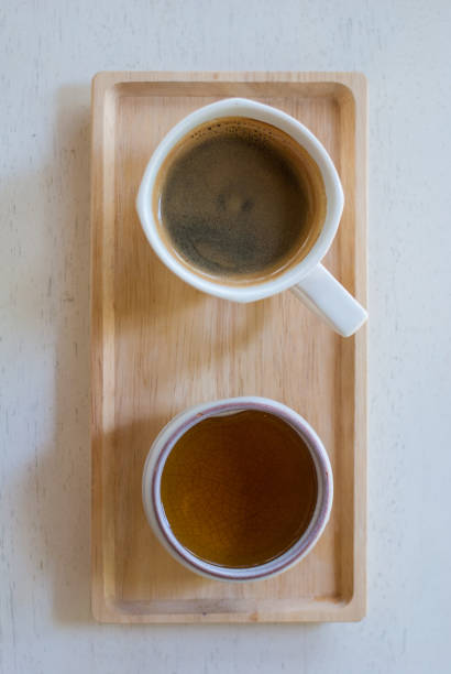 Black espresso coffee mug with thin crema placed on wooden tray with tea glass, peaceful moment
