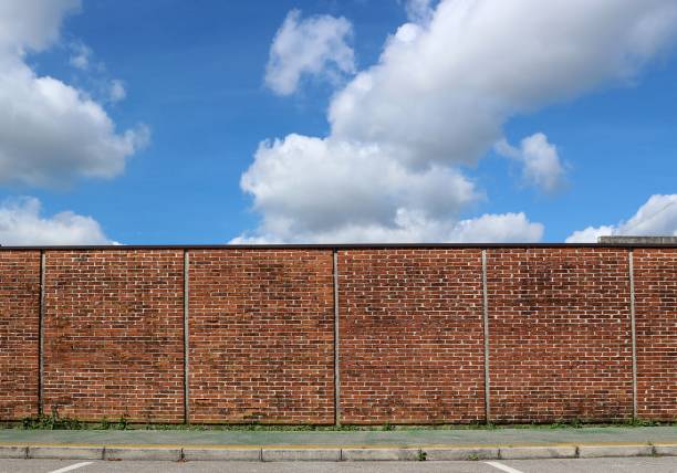 istock Brick wall and green sidewalk under blue sky with big clouds 959590468