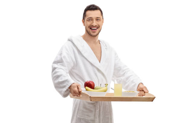 istock Young man in a bathrobe holding a breakfast tray 959594486