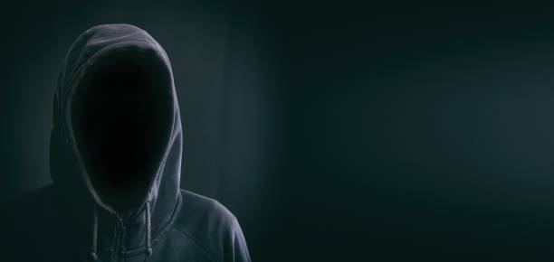 istock Hooded faceless man on black background 959600696