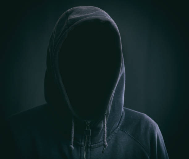 istock Hooded faceless man on black background 959600794