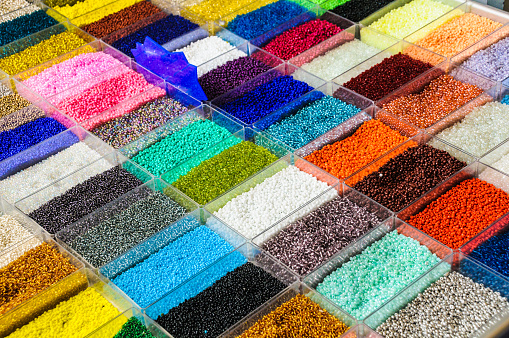 Tiny beads of many colors  and shapes are in plastic bins at a sidewalk shop in Athens, Greece