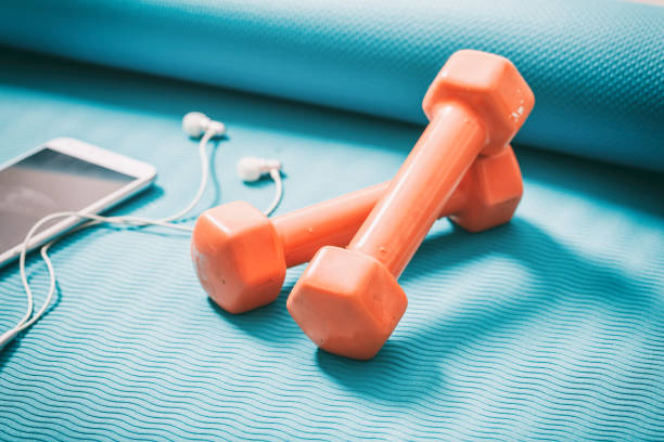 Dumbbells and a smartphone on a green yoga mat
