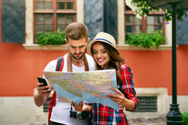 istock Beautiful Tourist Couple Traveling Using Map And Phone. 959613520