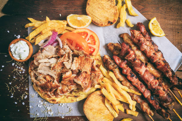 greek gyros dish and meat skewers on a wooden background - opa! souvlaki of greece imagens e fotografias de stock