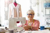 Senior fashion designer using a sewing machine in her workshop