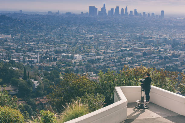 istock asian chinese female looking through telescope overlooking los angeles 959618948
