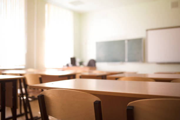 aula scolastica infondersi senza giovani studenti; vista sfocata della stanza di classe senza bambino o insegnante con sedie e tavoli nel campus. - school education desk nobody foto e immagini stock