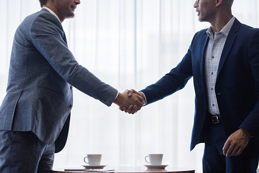 Two business men shaking hands with each other after a deal. Businesspeople shaking hands making a necessary agreement during a meeting.