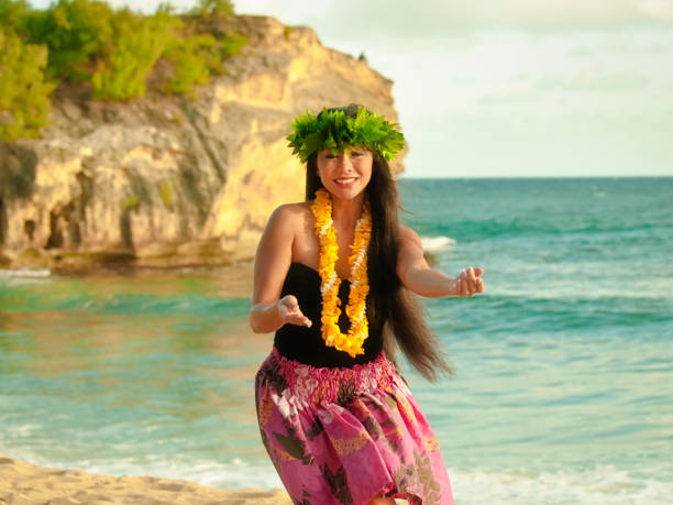 Hawaiian Hula Dancer on the Beach of Kauai A beautiful Hawaiian Hula dancer dancing on the beach of the tropical Hawaiian islands. She is wearing a contemporary Hula dance dress with a lei and flower headdress. Photographed in horizontal format with copy space in Kauai, Hawaii. hula dancer stock pictures, royalty-free photos & images