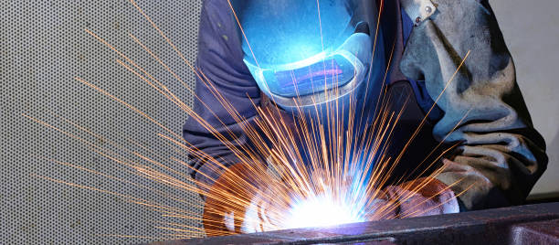 сварщик работает в промышленной компании - производство стальных компонентов - factory building flash стоковые фото и изображения