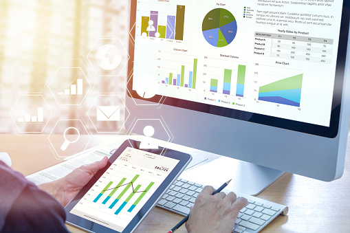 Businessman in front of modern computer with colorful pie and bar graphs analysing business performance accounting data