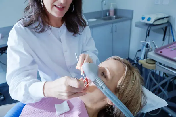 Female Caucasian dental hygienist dentist working with a patient in a dental clinic.She is in the process of a dental procedure working with anesthesia.