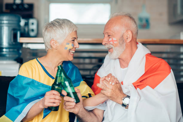 istock Happy couple holding hands and having celebratory toast while watching soccer 959634710