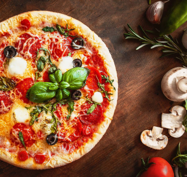 istock Hot pizza with Pepperoni  with vegetables and fresh ingredients on rustic wooden table. Pizza menu. View from above. 959635054