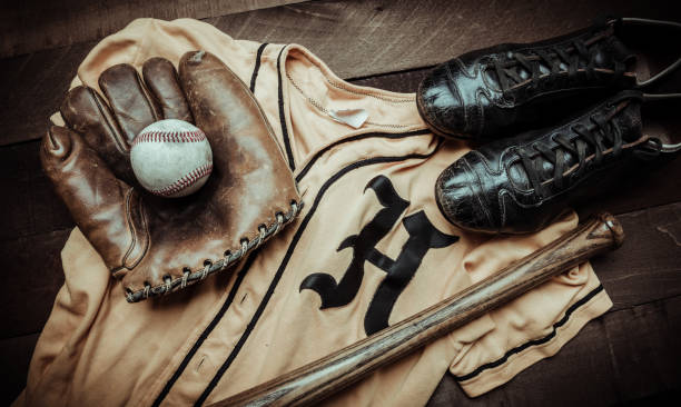 Vintage baseball gear on a wooden background A group of vintage baseball equipment, bats, gloves, baseballsand a jersey on wooden background old baseball stock pictures, royalty-free photos & images