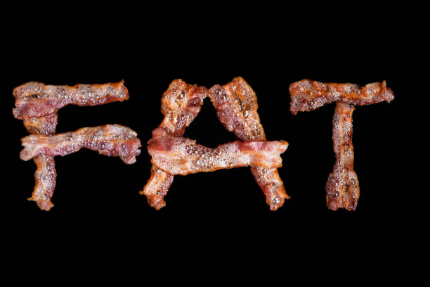 istock Bacon shaped as the word FAT on black background 959635624