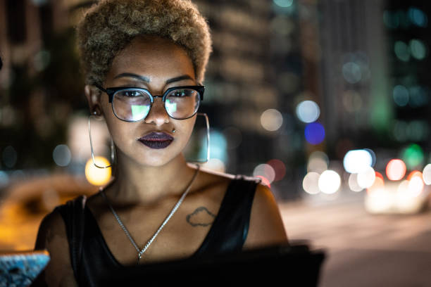 młoda kobieta za pomocą tabletu w nocy - lighting equipment defocused street light city zdjęcia i obrazy z banku zdjęć