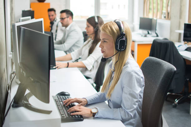 istock Portrait of beautiful young woman telephone operator with headset working on desktop computer in row in customer service call support helpline center 959638704