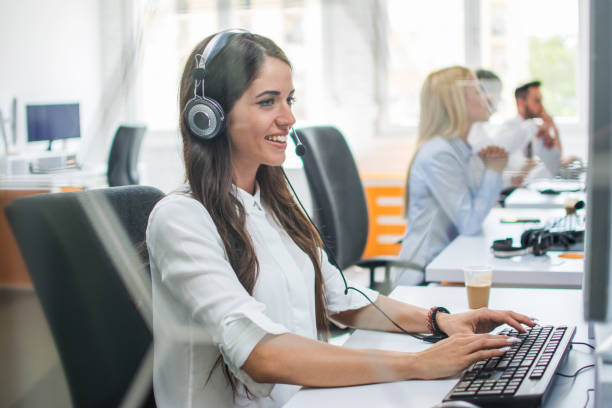 istock Smiling business woman with hands-free set working on computer and giving instructions online to customer. 959639158