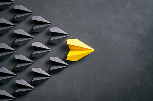 Conceptual photography with black and yellow paper airplanes on a smudged blackboard.