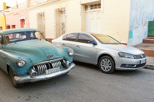 Trinidad, Cuba - December 8, 2017: New car compared to an old car in Trinidad of Cuba