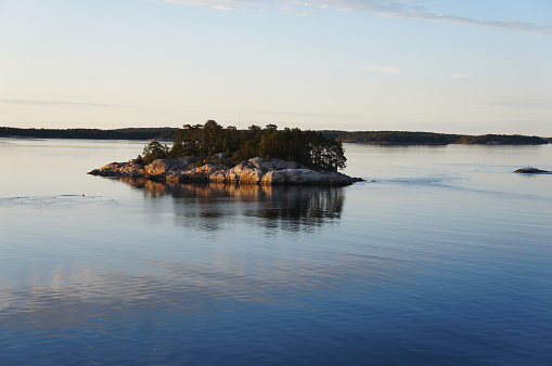 Small rocky island in archipelago of Turku, Finland in sea at sunset