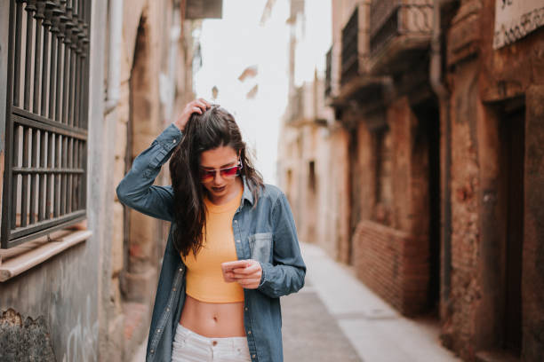 istock Young woman walking in a city while checking her smartphone 959674314