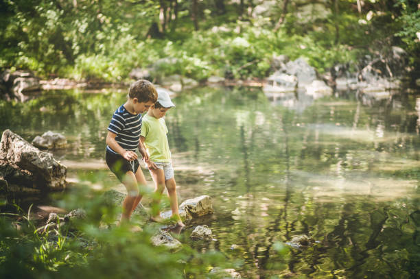 Boys Playing Next To The Lake In The Forest stock photo