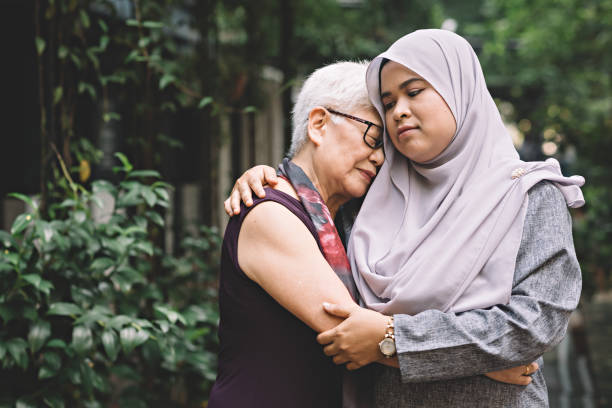 una femmina asiatica cinese maturata parlando e abbracciando una femmina malese asiatica di mezza età con espressione triste - malaysian person family asian ethnicity mother foto e immagini stock