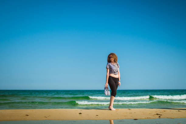 istock Woman enjoying summer walk on the beach 959694136
