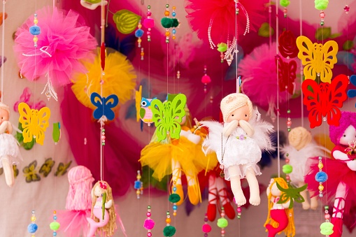 Handmade colorful dolls, butterflies and other toys hanging on threads