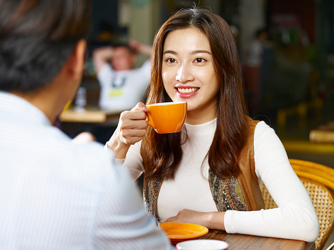 young asian couple lovers sitting at table chatting talking face to face in coffee shop.