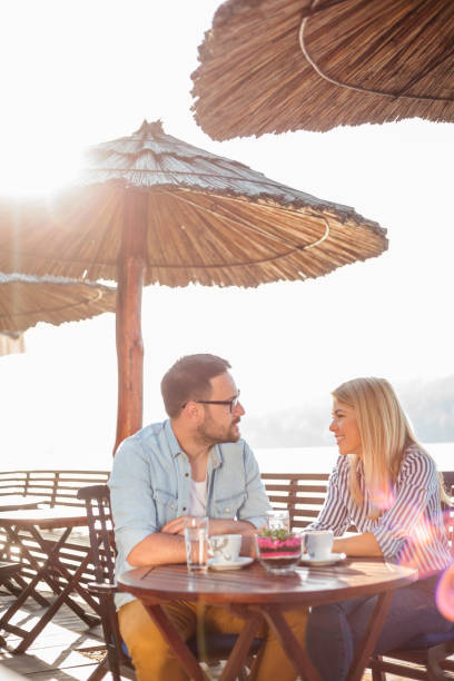 istock Young couple relaxing and drinking coffee in a cafe by the river 959712588