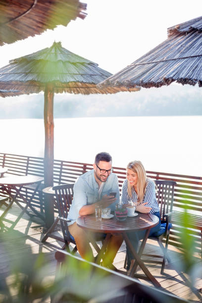istock Happy young couple drinking coffee and talking in a riverside cafe 959712940